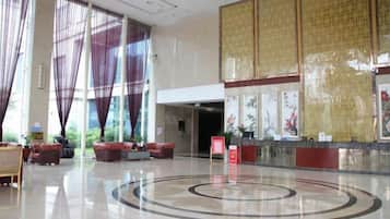 A spacious lobby with a reception desk, seating area, and large windows.