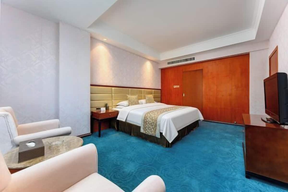 A hotel room with a bed, a TV, a desk, and a chair.