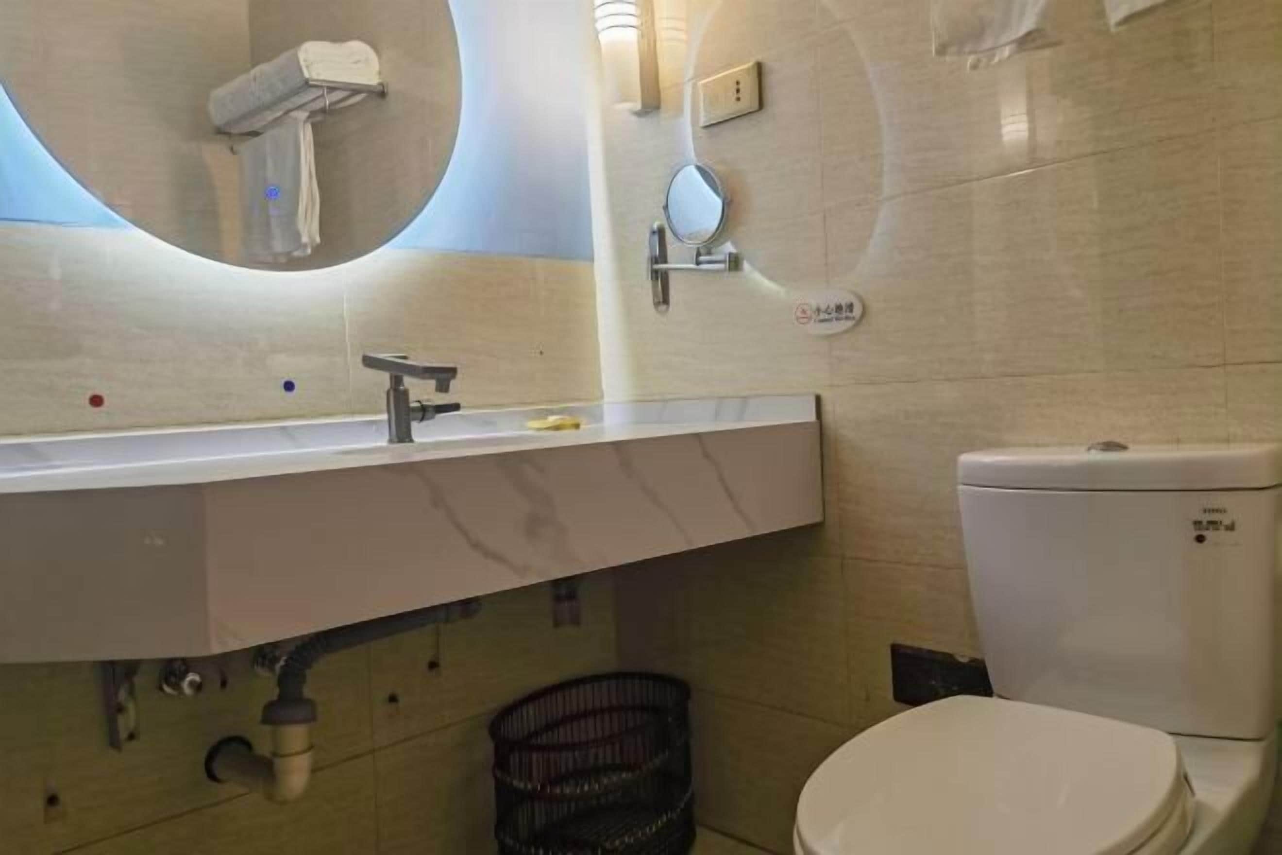 Ein Badezimmer mit einem weißen Waschbecken, Spiegel und WC.