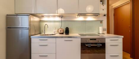 Una cocina moderna con armarios blancos, electrodomésticos de acero inoxidable y un horno empotrado.
