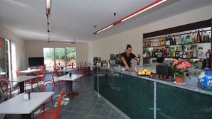 A restaurant with a bar area, outdoor seating, and a view of the outdoors. - Residence Borgoverde Two-room Apartment 5 Pax (Imperia)