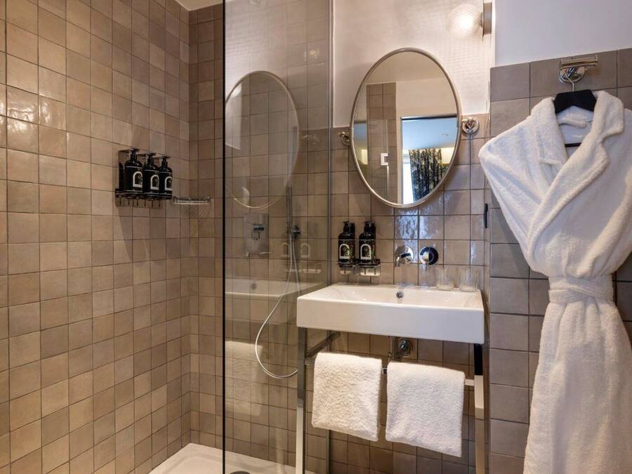 Une salle de bain moderne avec une douche à parois de verre, un lavabo blanc et un peignoir suspendu à un porte-serviettes.