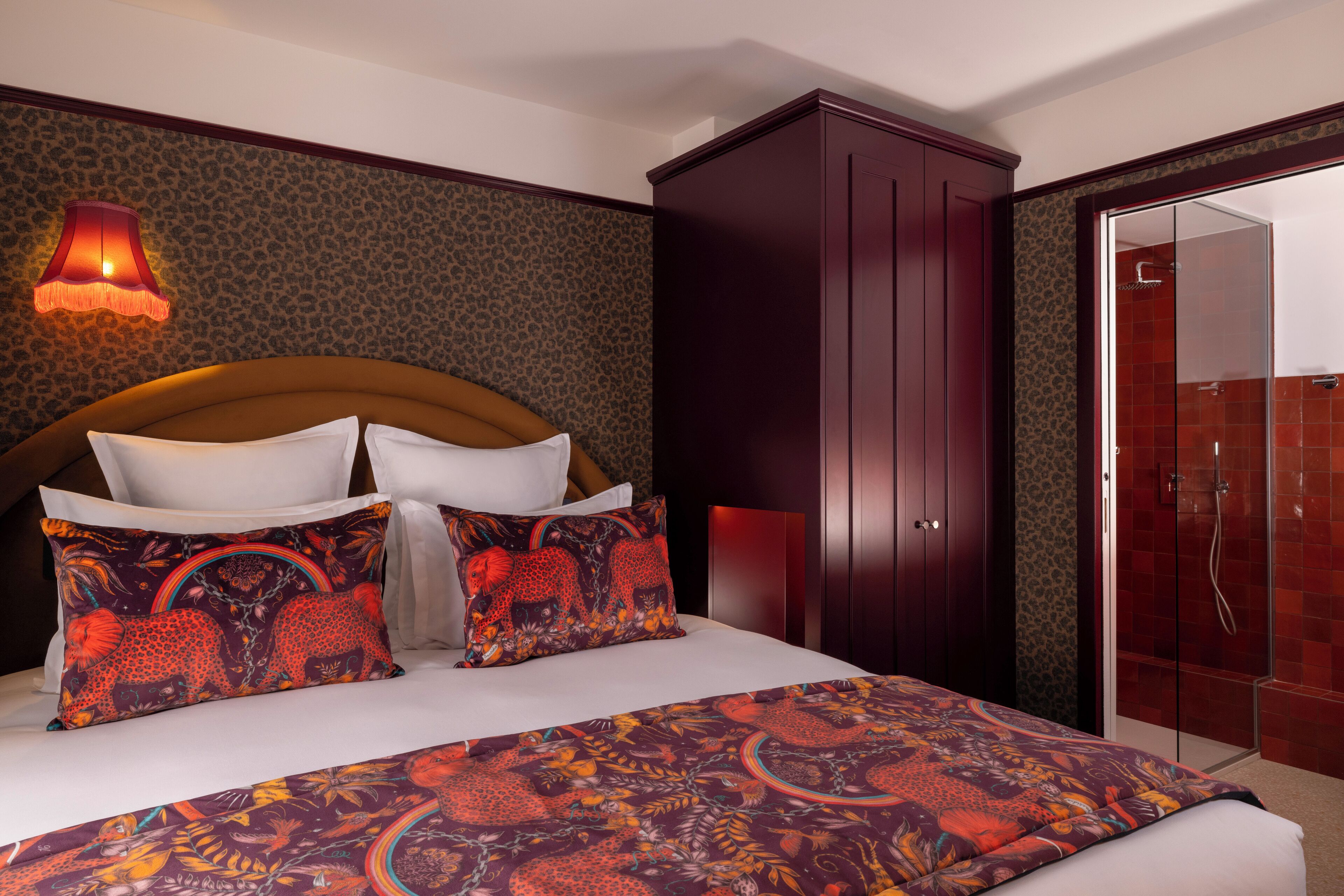 A hotel room with a large bed, a wardrobe, and a shower area.