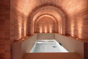 A modern spa with a brick arch ceiling and a central bathtub. - Ginette à la Folie (Paris)