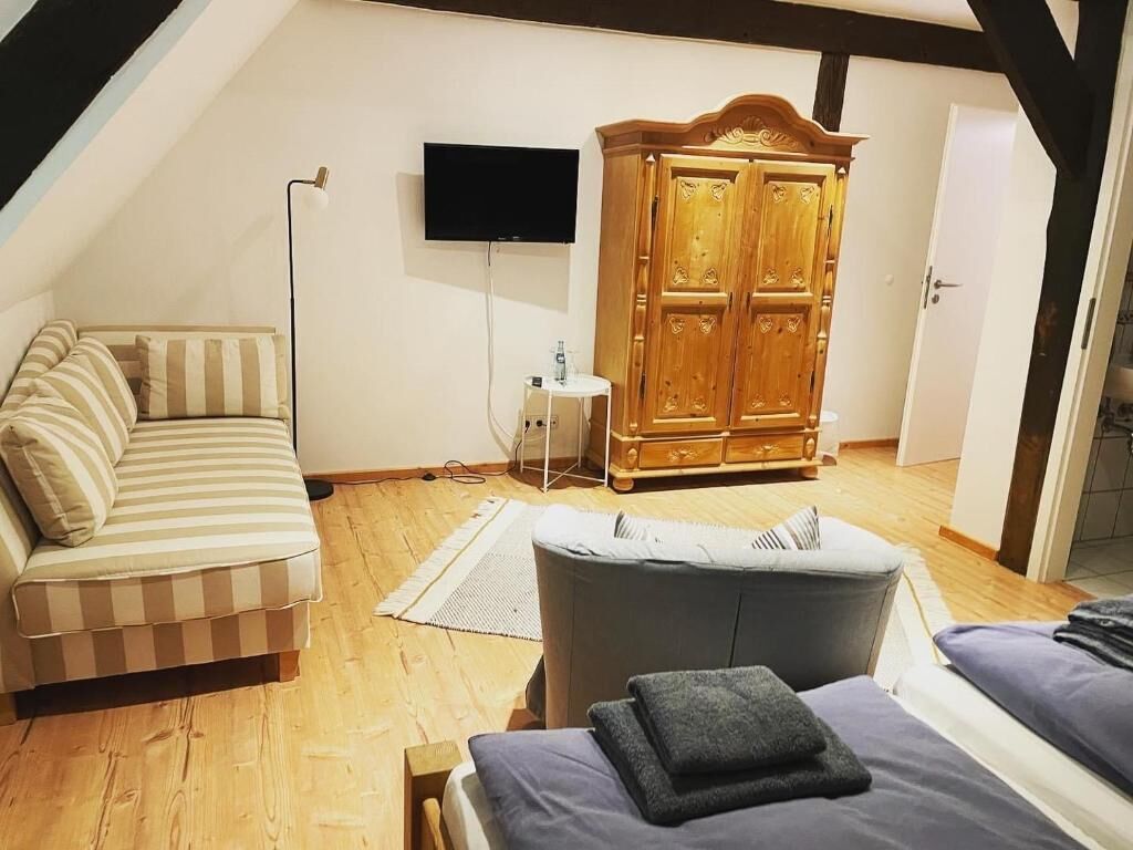 A cozy room with a sofa, a bed, and a wooden wardrobe.