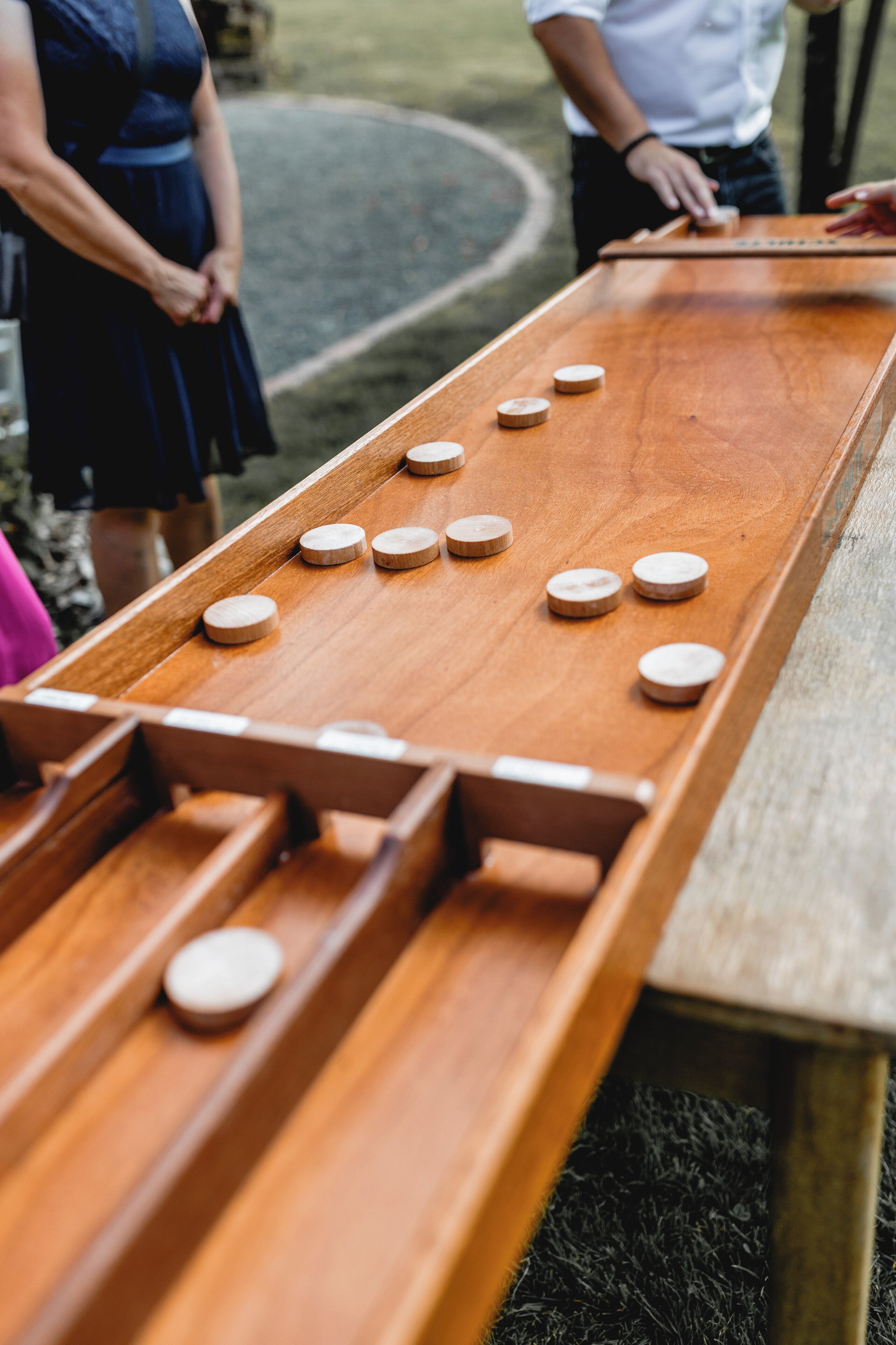 Ein Holztisch für Brettspiele mit Spielsteinen und einer Person in der Nähe.