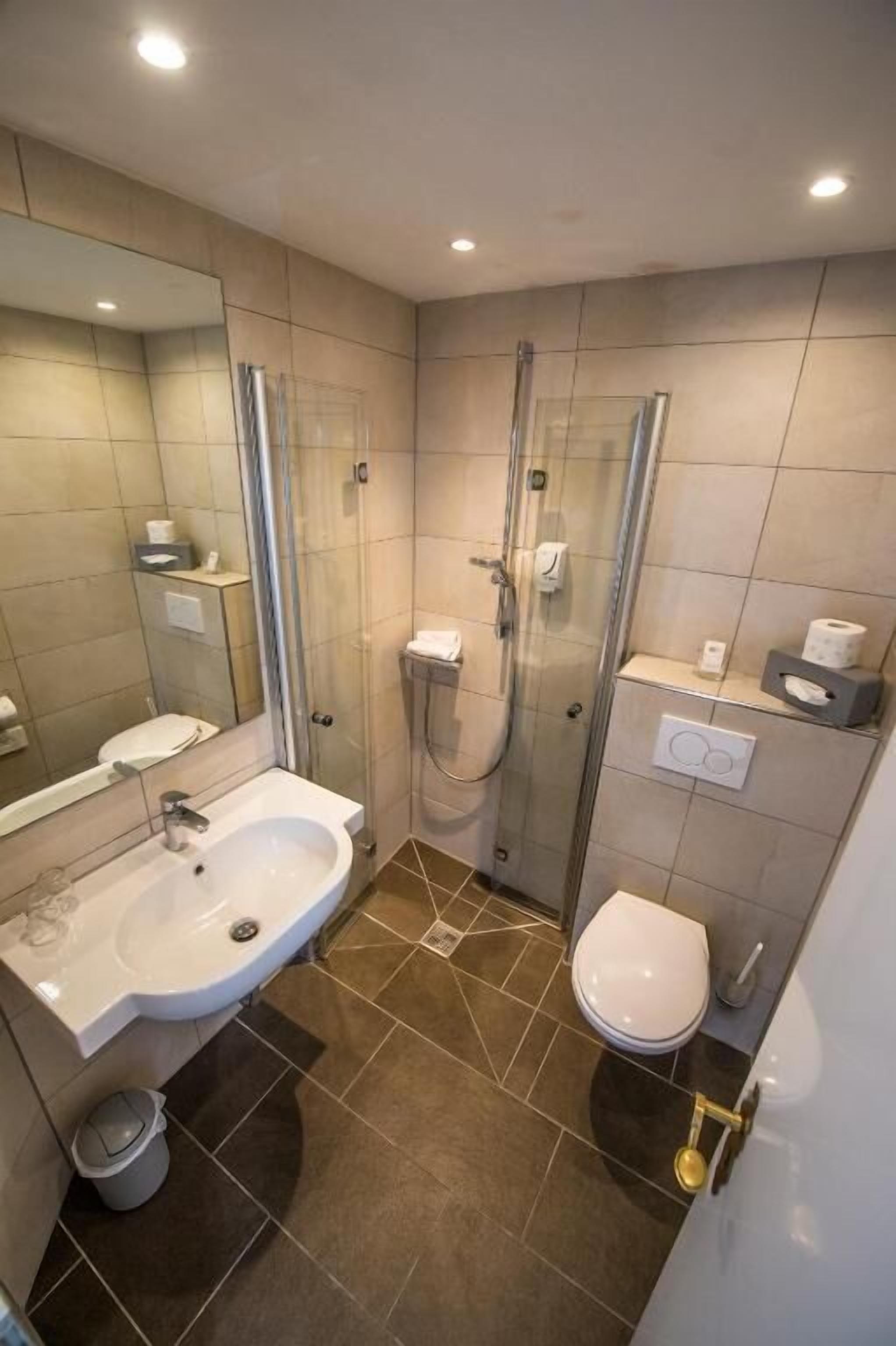 Un bagno moderno con doccia vetrata, lavandino bianco e water.