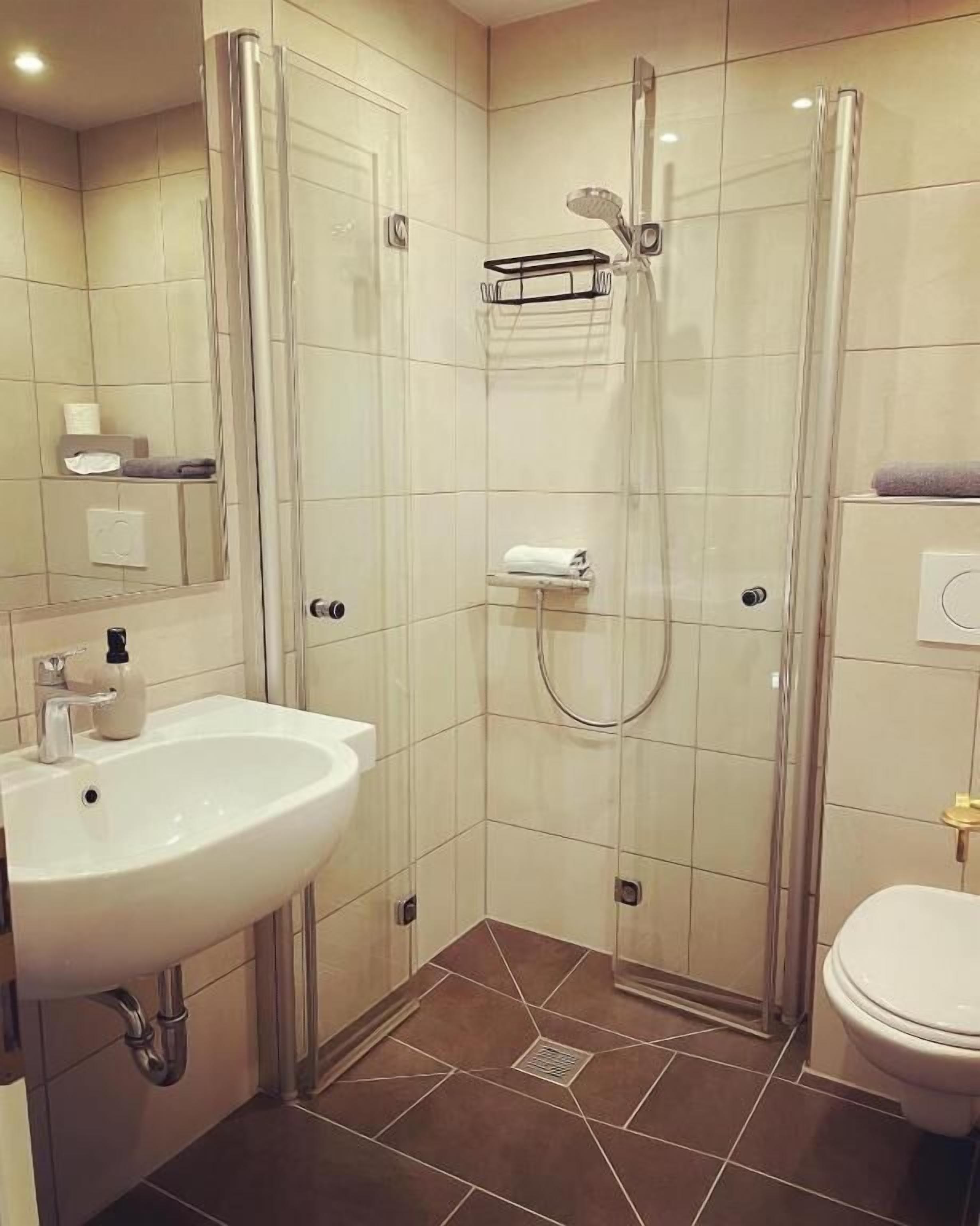 Une salle de bain moderne avec une douche à parois de verre, un lavabo blanc et des toilettes.