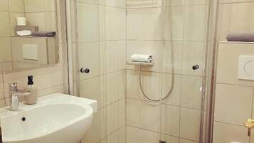 Une salle de bain moderne avec une douche à parois de verre, un lavabo blanc et des toilettes.