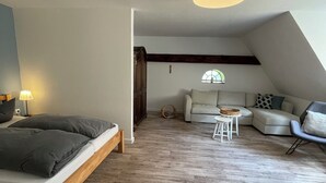 Ein modernes Schlafzimmer im Loft-Stil mit einem Holzbett, einer Couch und einem kleinen Tisch.
