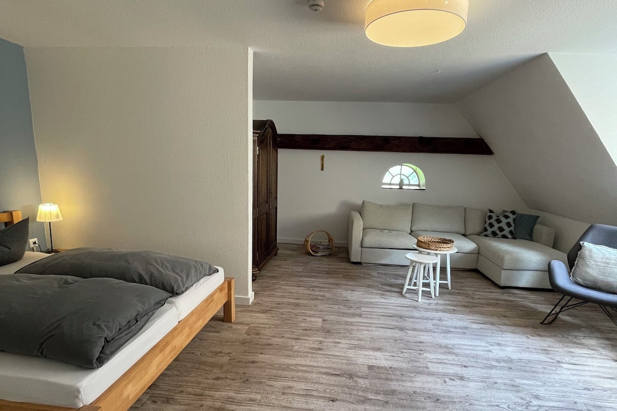 Un dormitorio estilo loft moderno con cama de madera, un sofá y una pequeña mesa.