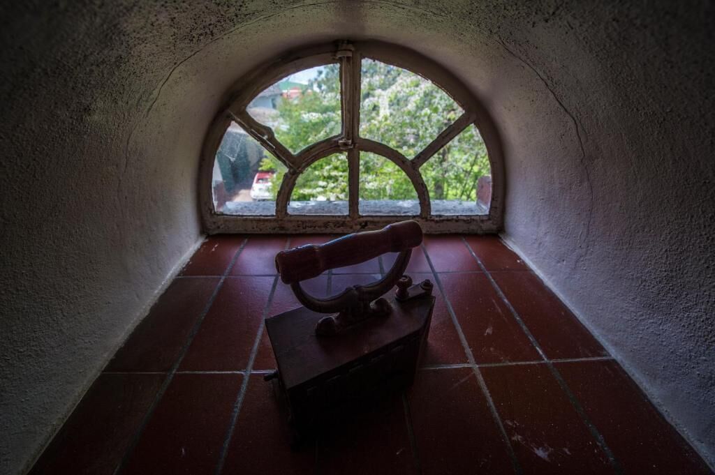 A narrow, arched window with a view of greenery outside.