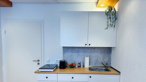 A compact kitchen with white cabinets, a wooden countertop, a sink, and a small plant. - Großes Apartment an der Loreley (Sankt Goar)