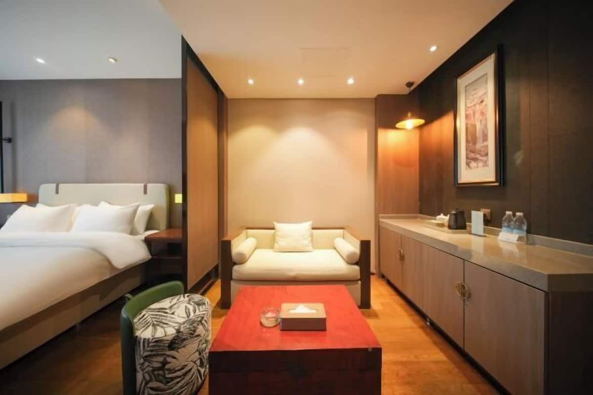 Ein Hotelzimmer mit Bett, Sofa, Couchtisch, Sessel und Schrank.