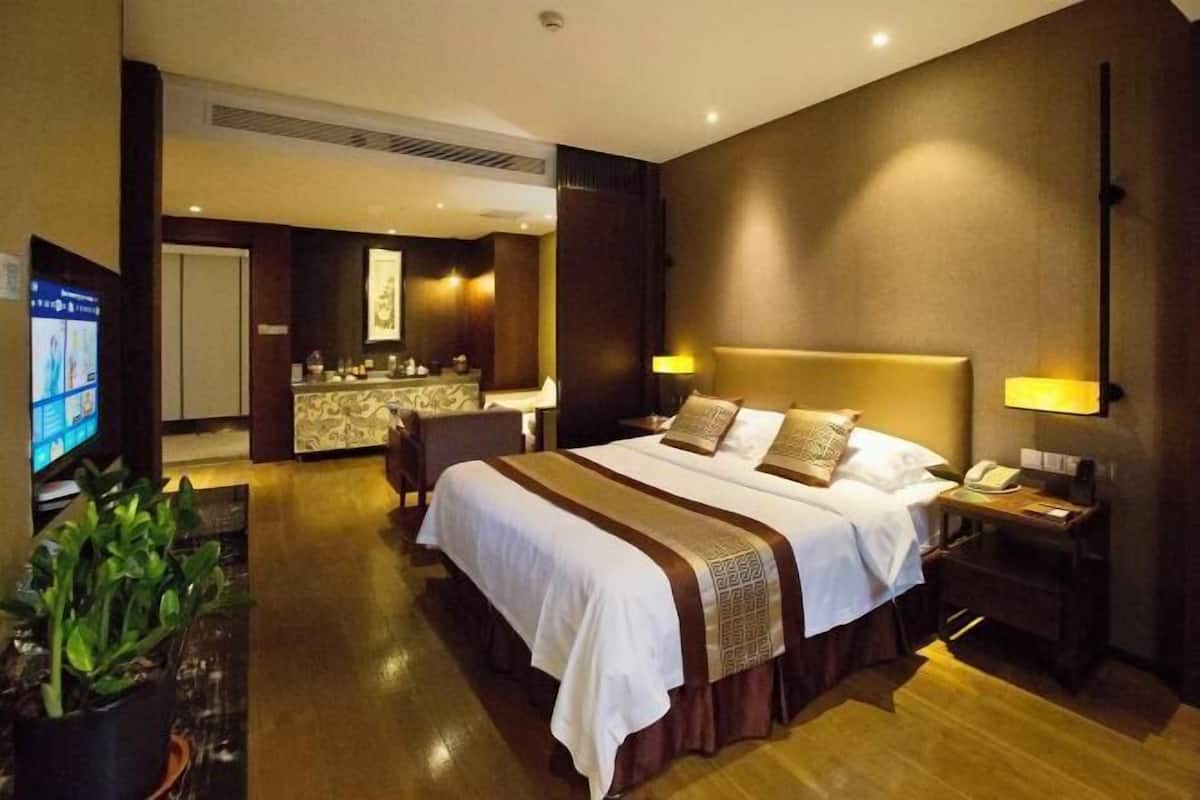 Ein Hotelzimmer mit einem großen Bett, Nachttischen, einem Schreibtisch und einem Fernseher.