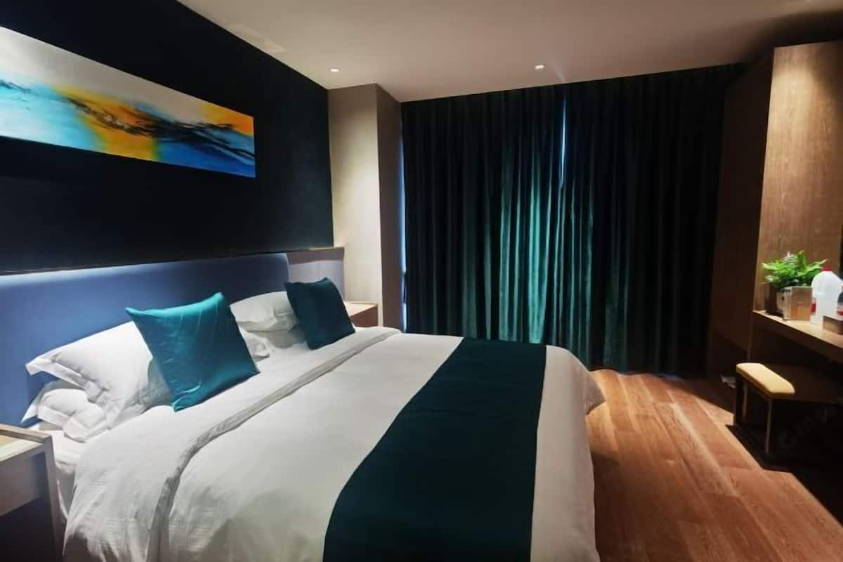 Ein modernes Hotelzimmer mit einem großen Bett, einem Schreibtisch und einem Bild an der Wand.
