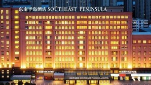 Un hotel de varios pisos con un letrero llamativo que dice 'Southeast Peninsula Hotel'.