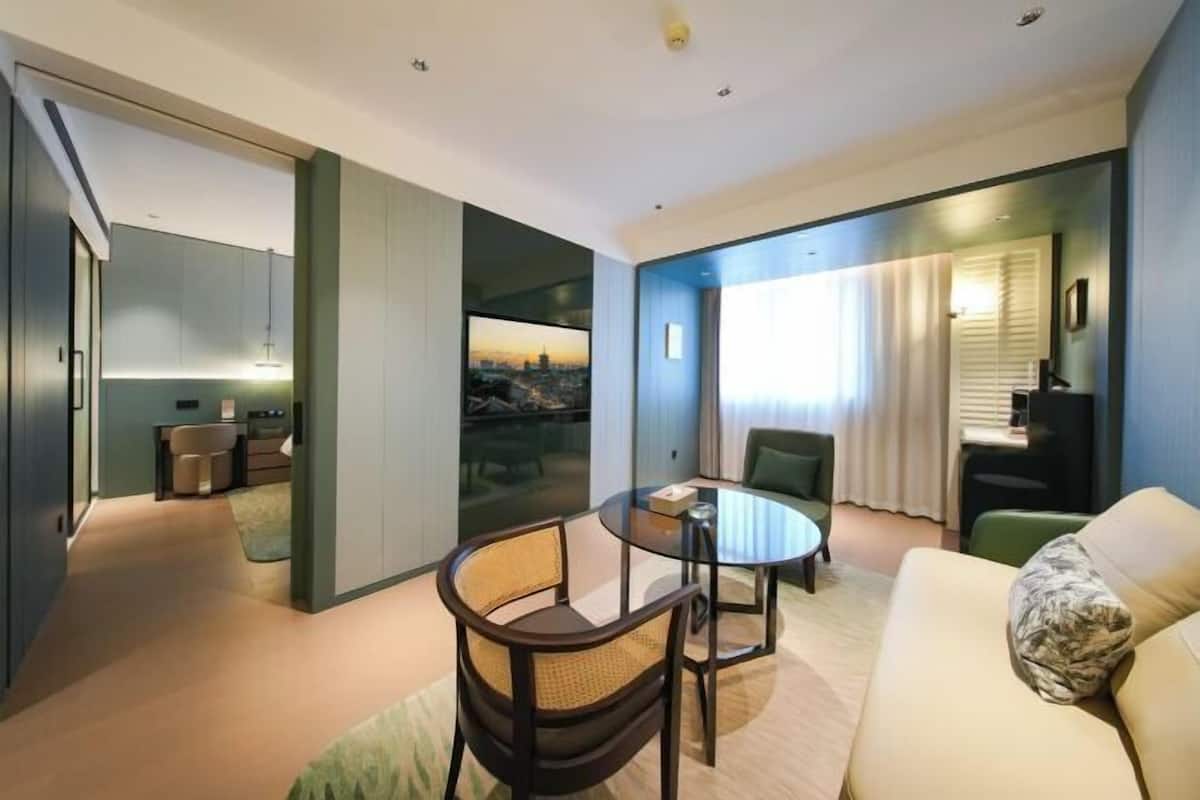 Ein modernes Hotelzimmer mit einem Glastisch, einer Couch und Blick auf die Stadtlandschaft.