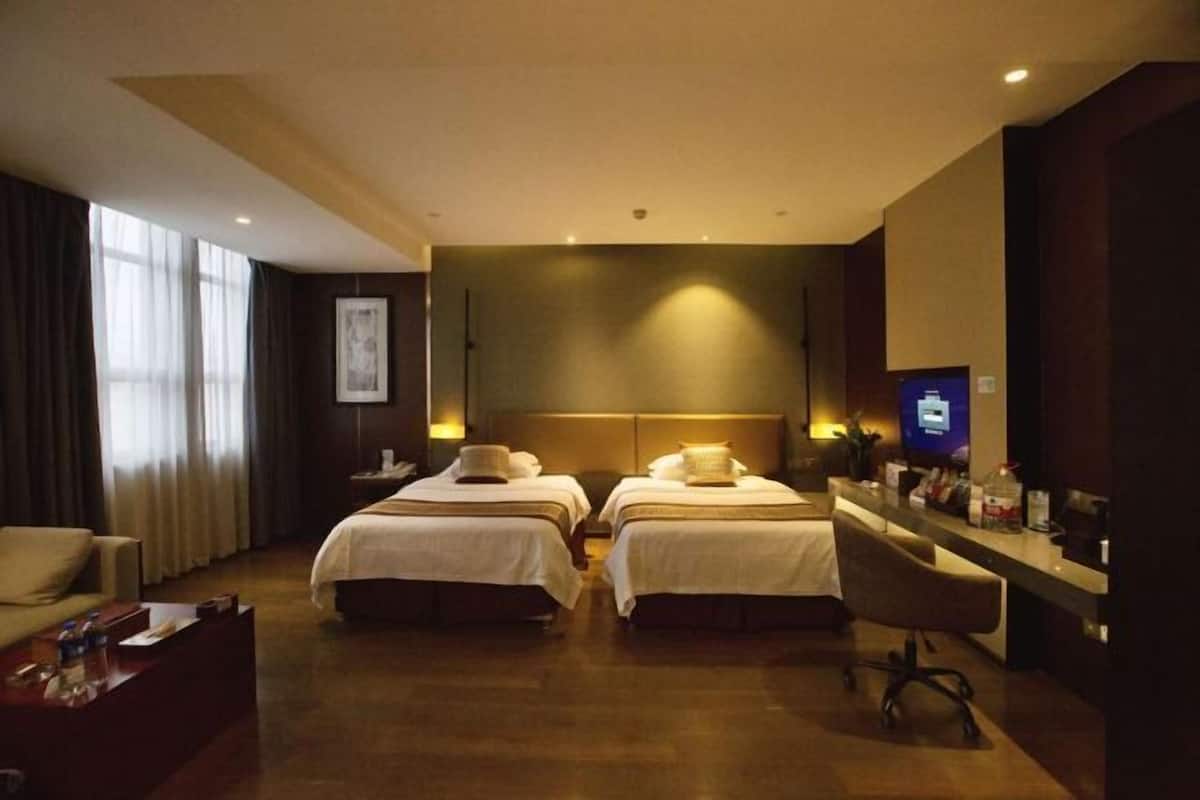 Ein Hotelzimmer mit zwei Betten, einem Schreibtisch, einem Stuhl und einem Fernseher.