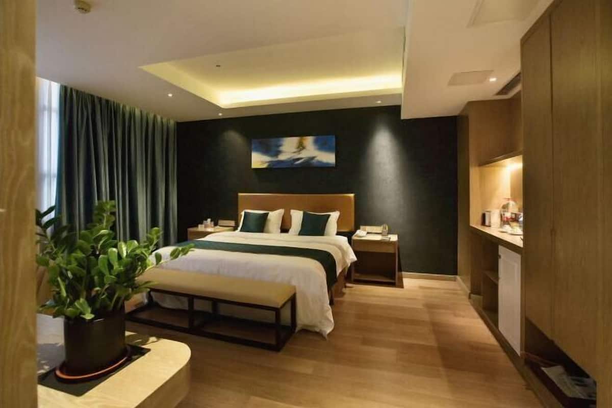 Ein modernes Hotelzimmer mit einem großen Bett, Nachttischen, einem Schreibtisch und einer Zimmerpflanze.