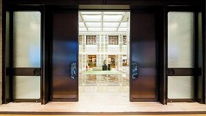 Entrada de hotel con mostrador de recepción, zona de espera y vista al vestíbulo.