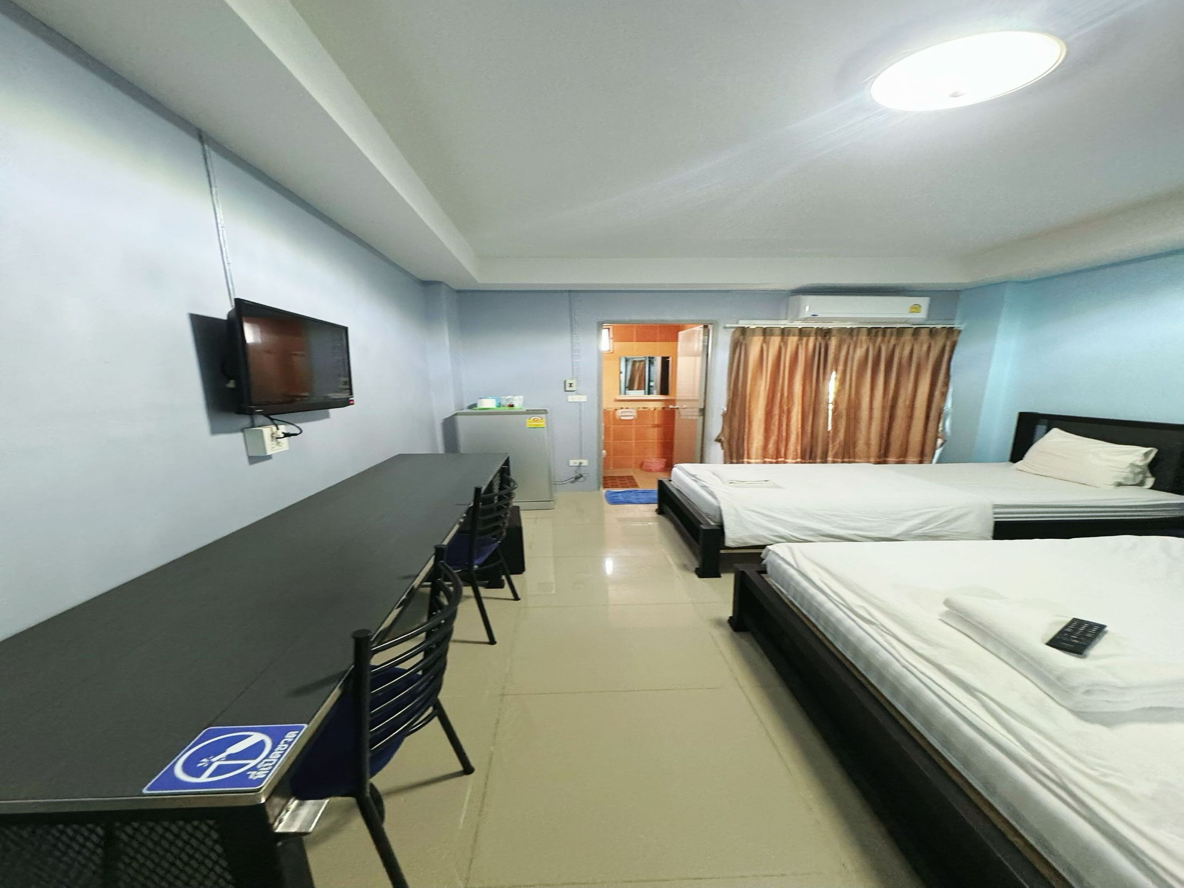 Une chambre d’hôtel équipée d’un lit, d’un bureau, d’une chaise, d’une télévision et d’une petite kitchenette.