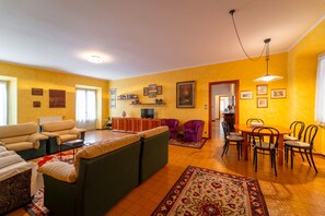 Een woonkamer met een bank, stoelen, een eettafel en een televisie.