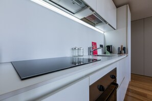 Une cuisine moderne dotée d’un élégant plan de travail noir, d’une hotte en acier inoxydable et d’un four encastré.