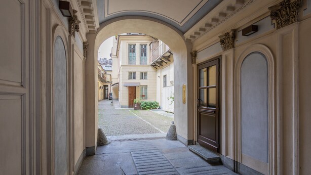 A corridor with stone flooring, an archway, and a building entrance. - La Casa del Mercato by Wonderful Italy (Turin)