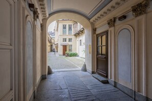 A corridor with stone flooring, an archway, and a building entrance. - La Casa del Mercato by Wonderful Italy (Turin)