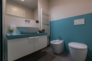 Une salle de bain avec un lavabo blanc, un bidet et des toilettes.
