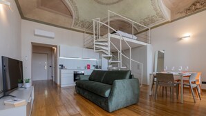 A modern living space with a staircase to an upper level, a dining area, and a kitchenette. - La Casa del Mercato by Wonderful Italy (Turin)
