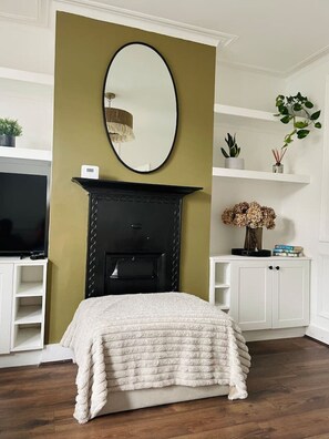 Cozy retreat with a central fireplace, white shelving units, and a large mirror above.