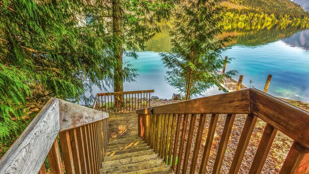 A wooden staircase leading to a lakeside platform with a view of a calm lake and surrounding forest. - Yellow Tail Cabin in Hoodsport (Hoodsport)