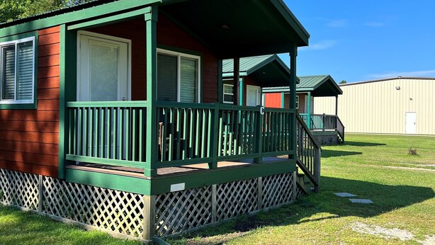 A single-story mobile home with a green porch and a fenced yard. - Deluxe Creekside Cabin nearby Blount's Creek! (Chocowinity)