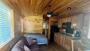A cabin interior with a wooden ceiling, a sofa, a bed, a kitchen area, and a dining table. - Deluxe Creekside Cabin nearby Blount's Creek! (Chocowinity)