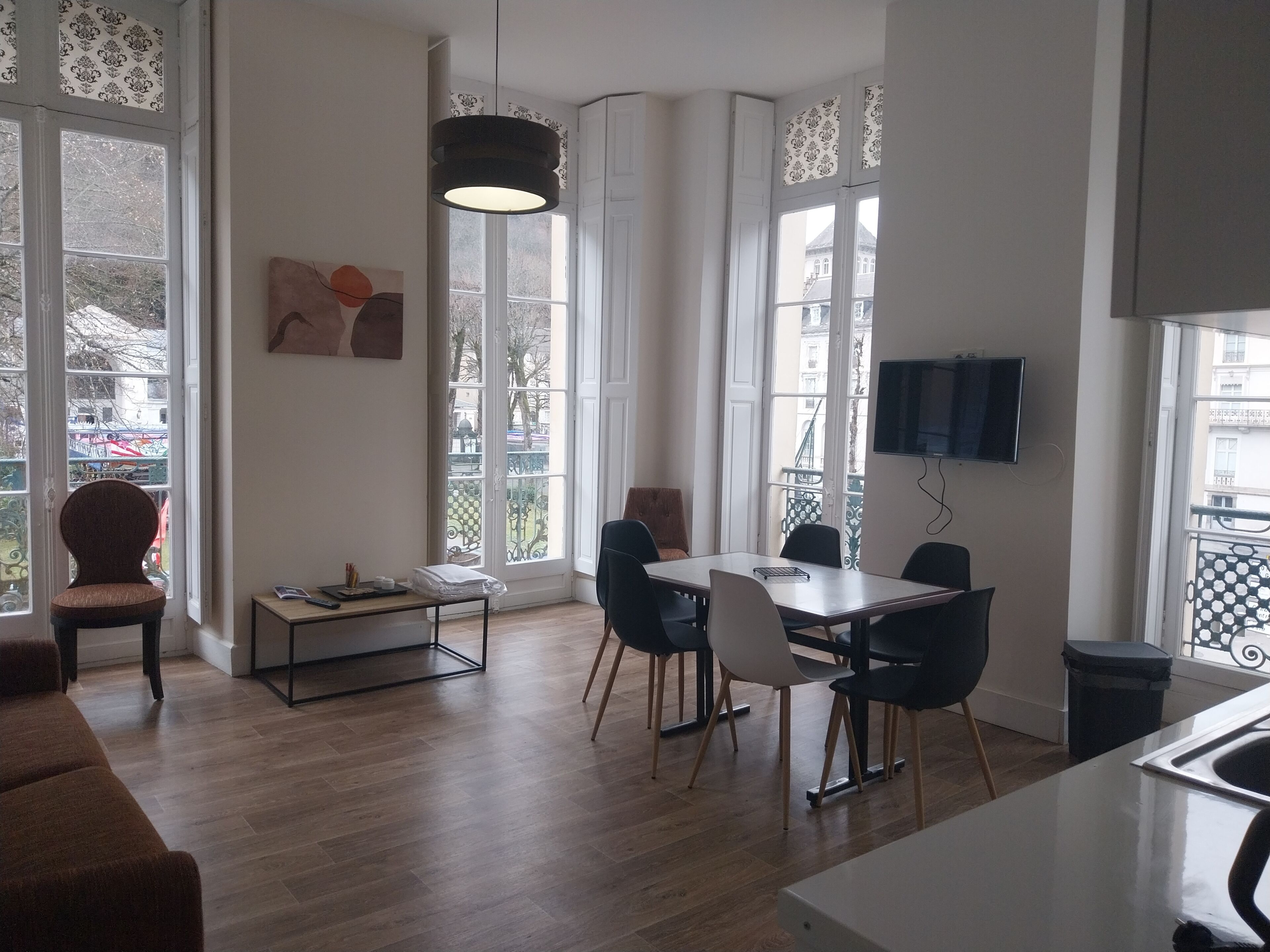 Ein modernes Wohnzimmer mit Essbereich, großen Fenstern und einem Flachbildfernseher.