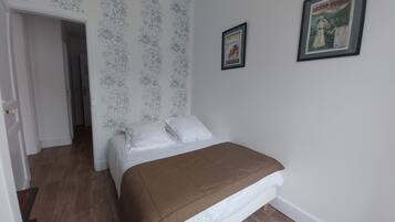 A bedroom with a bed, a door, a hallway, and a poster on the wall.