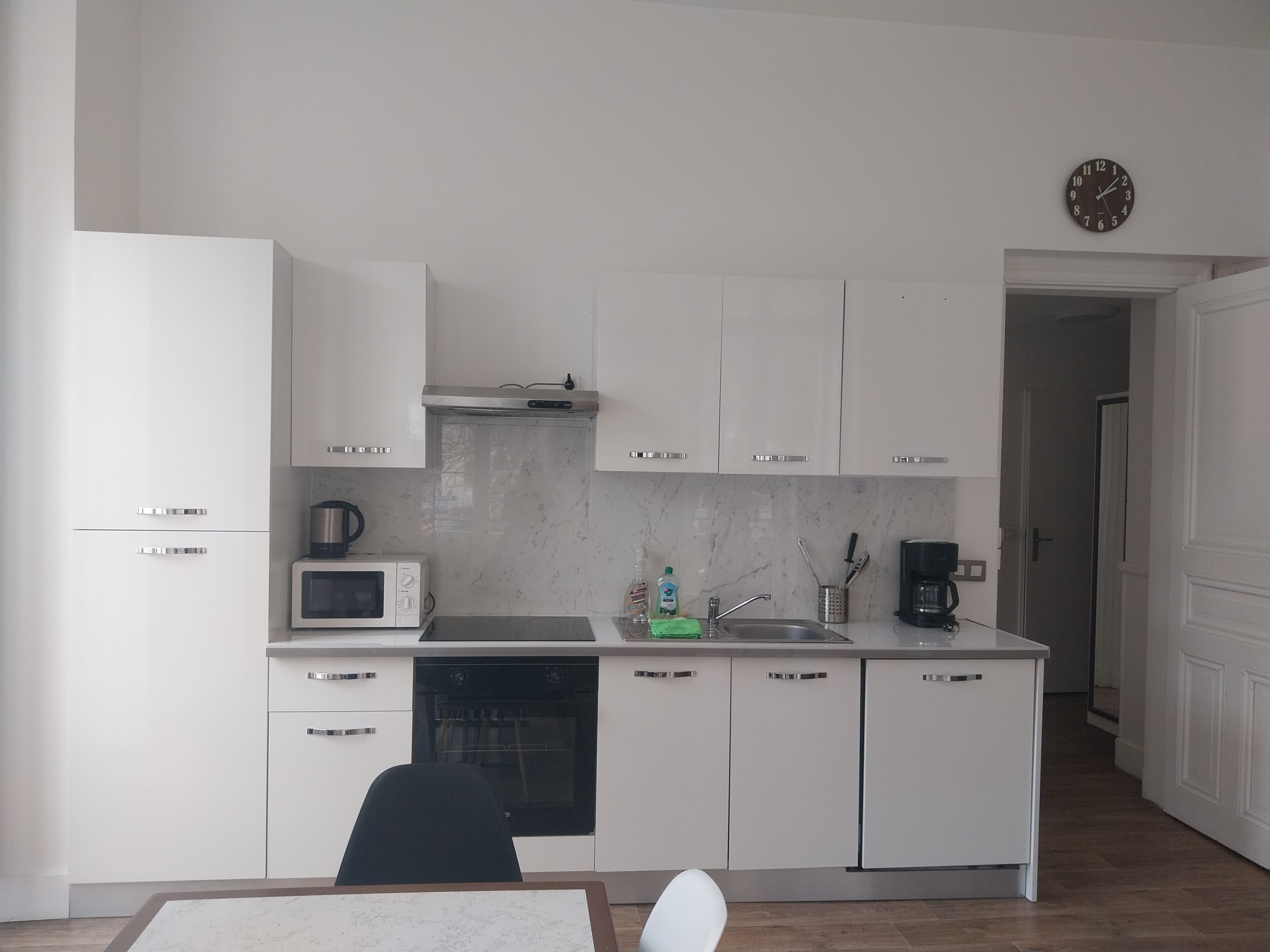 A modern kitchen with white cabinetry, a microwave, an oven, and a coffee maker.