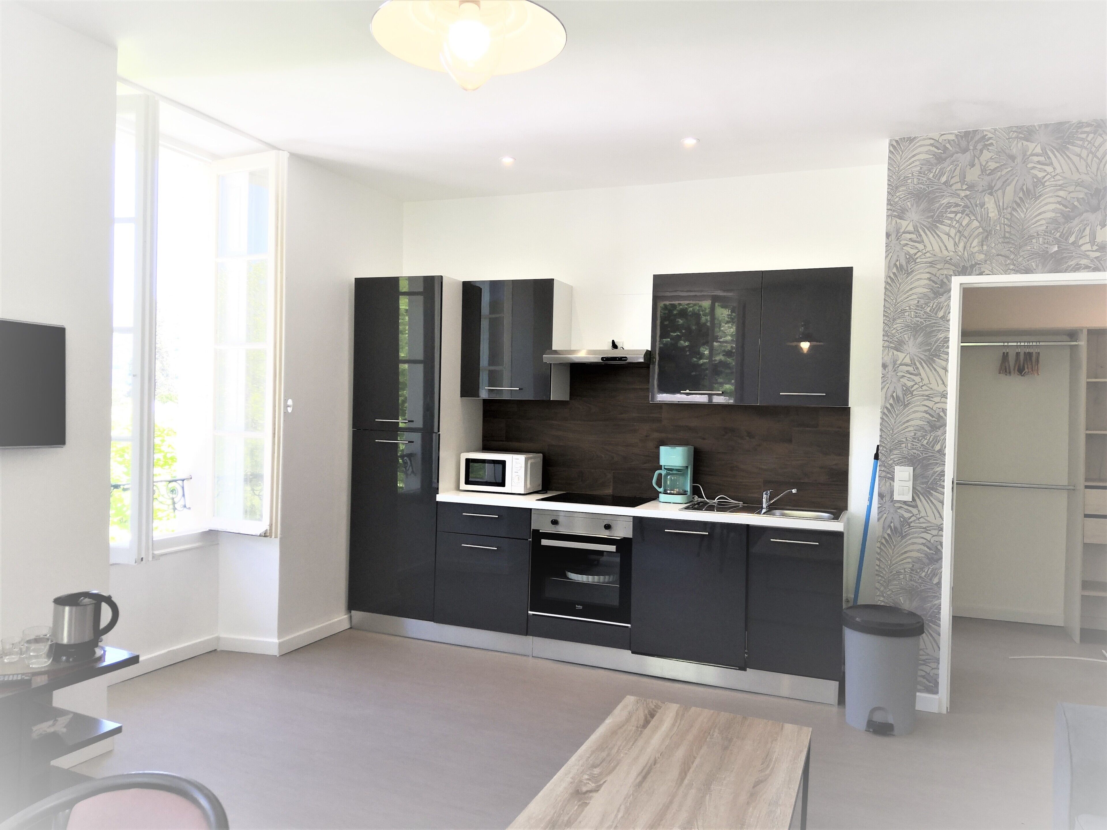 A modern kitchen with black cabinets, a microwave, and a coffee machine.