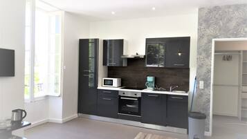 A modern kitchen with black cabinets, a microwave, and a coffee machine.