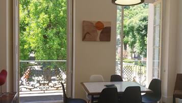 A dining area with a table and chairs, a hanging light fixture, and a view of greenery outside.
