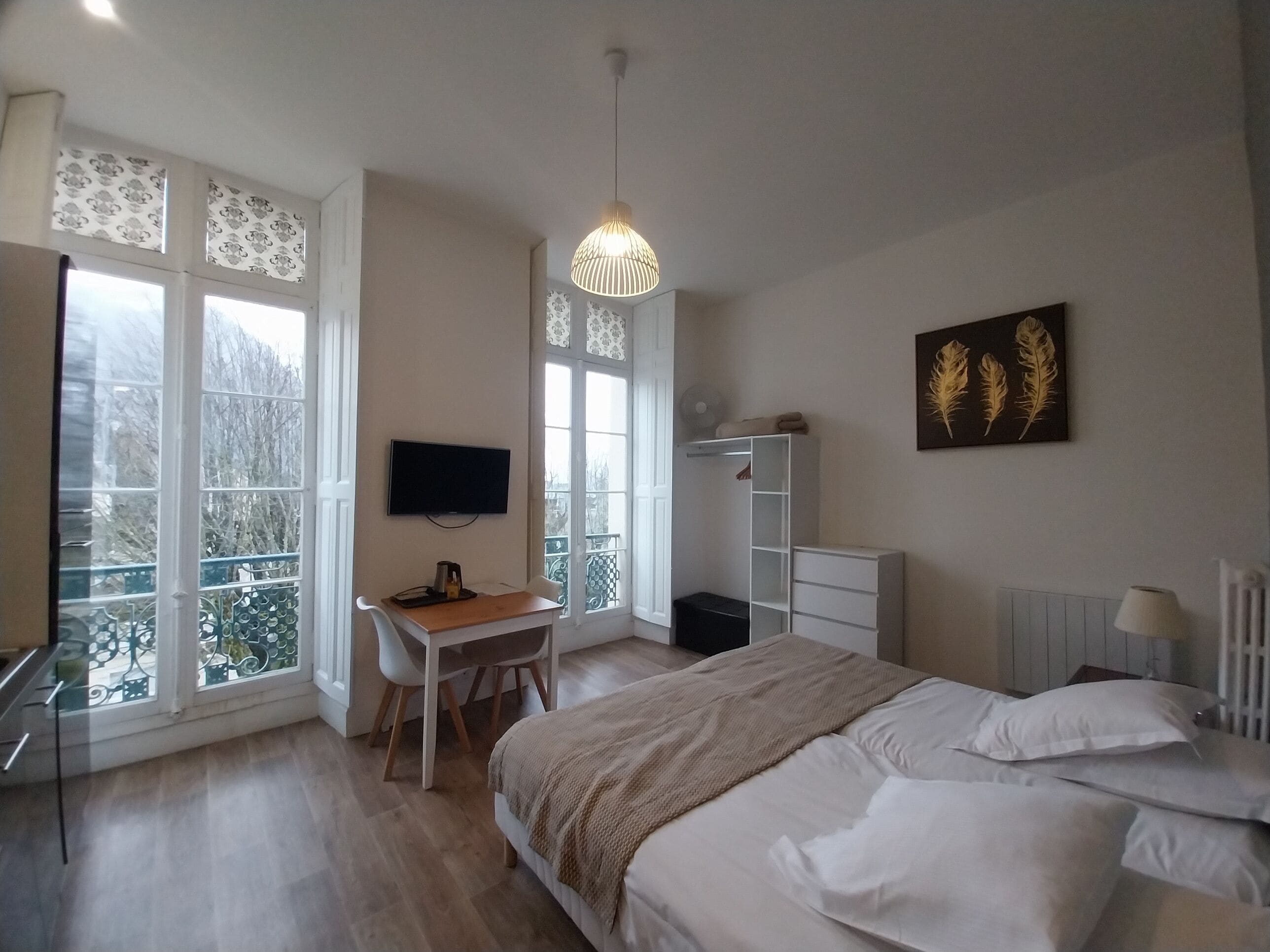 Une chambre à coucher comprenant un lit, un bureau, une chaise, un téléviseur et un radiateur.