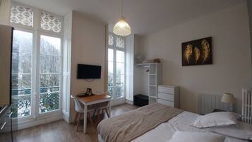 Une chambre à coucher comprenant un lit, un bureau, une chaise, un téléviseur et un radiateur.