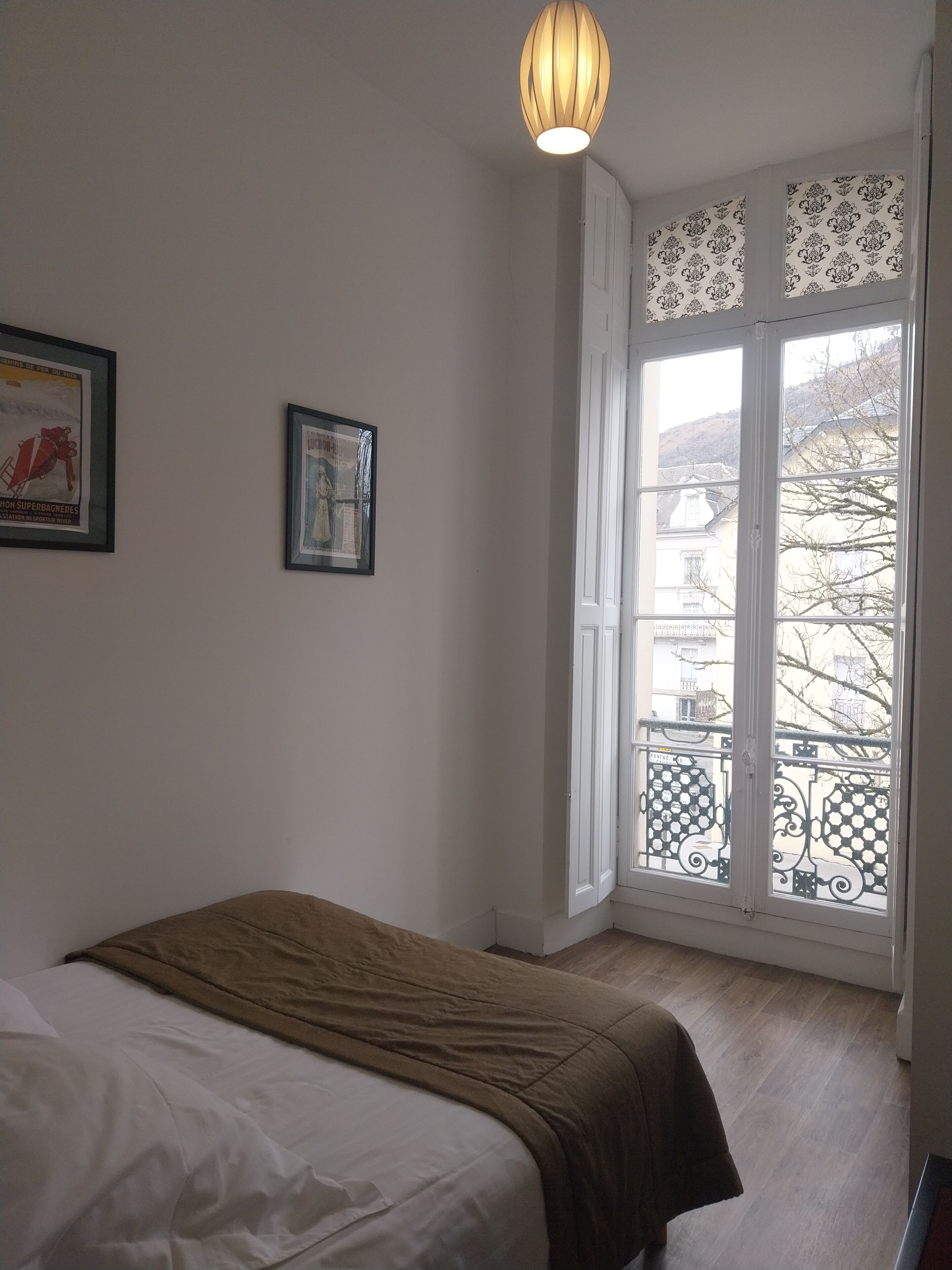Un dormitorio con cama, ventana con vistas y lámpara.