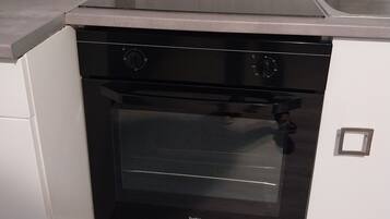 A kitchen with a black oven, white cabinets, and a stainless steel countertop.