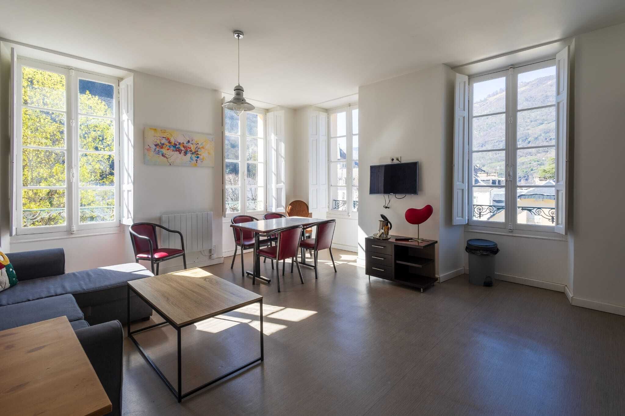 Un grand salon comprenant une table à manger, des chaises rouges, un canapé et un téléviseur.