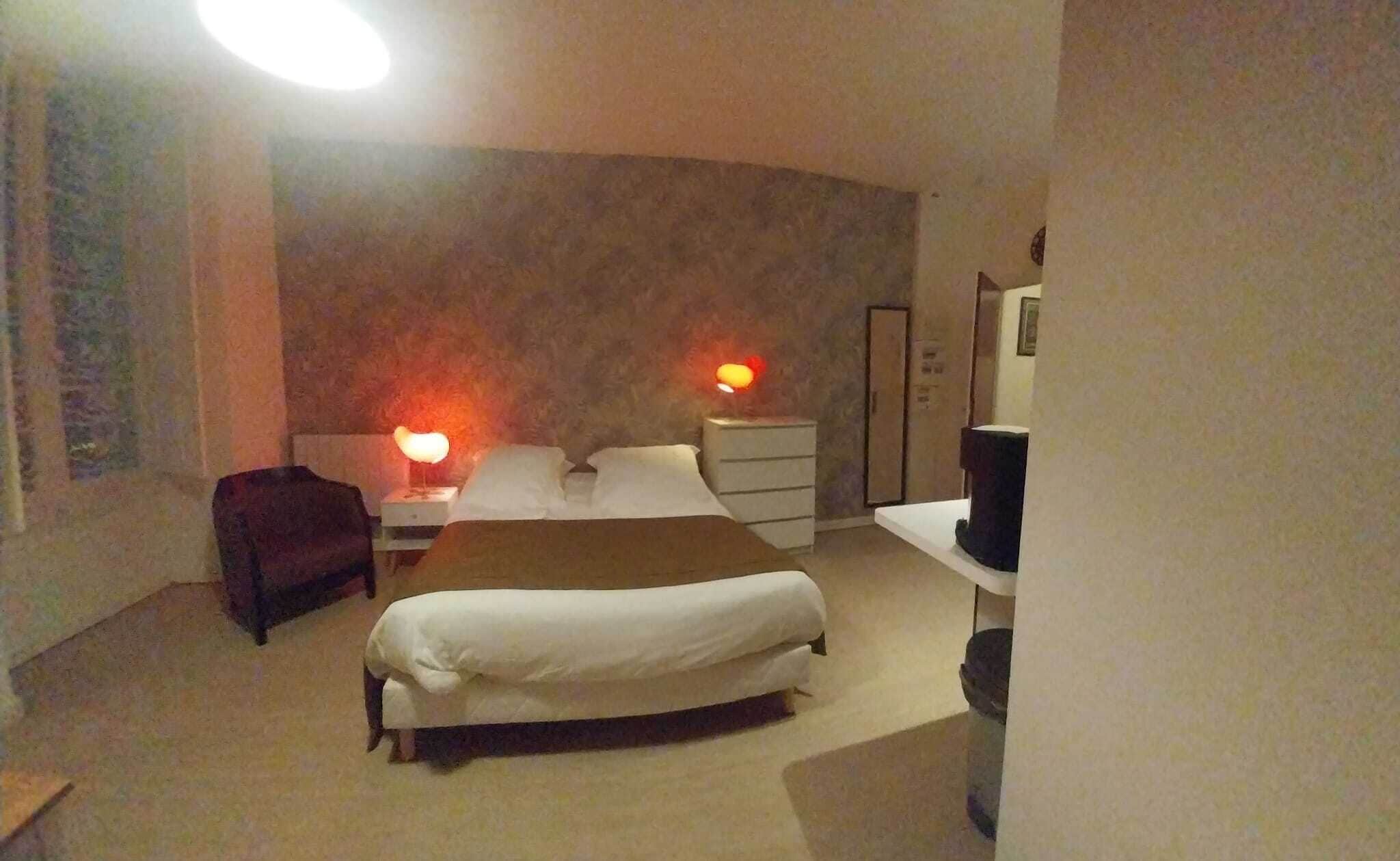 Une chambre à coucher comprenant un lit, des tables de chevet, une commode, une chaise et un téléviseur.
