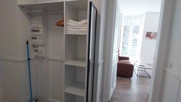 A room with a white wardrobe, a blue mop, and a brown sofa.