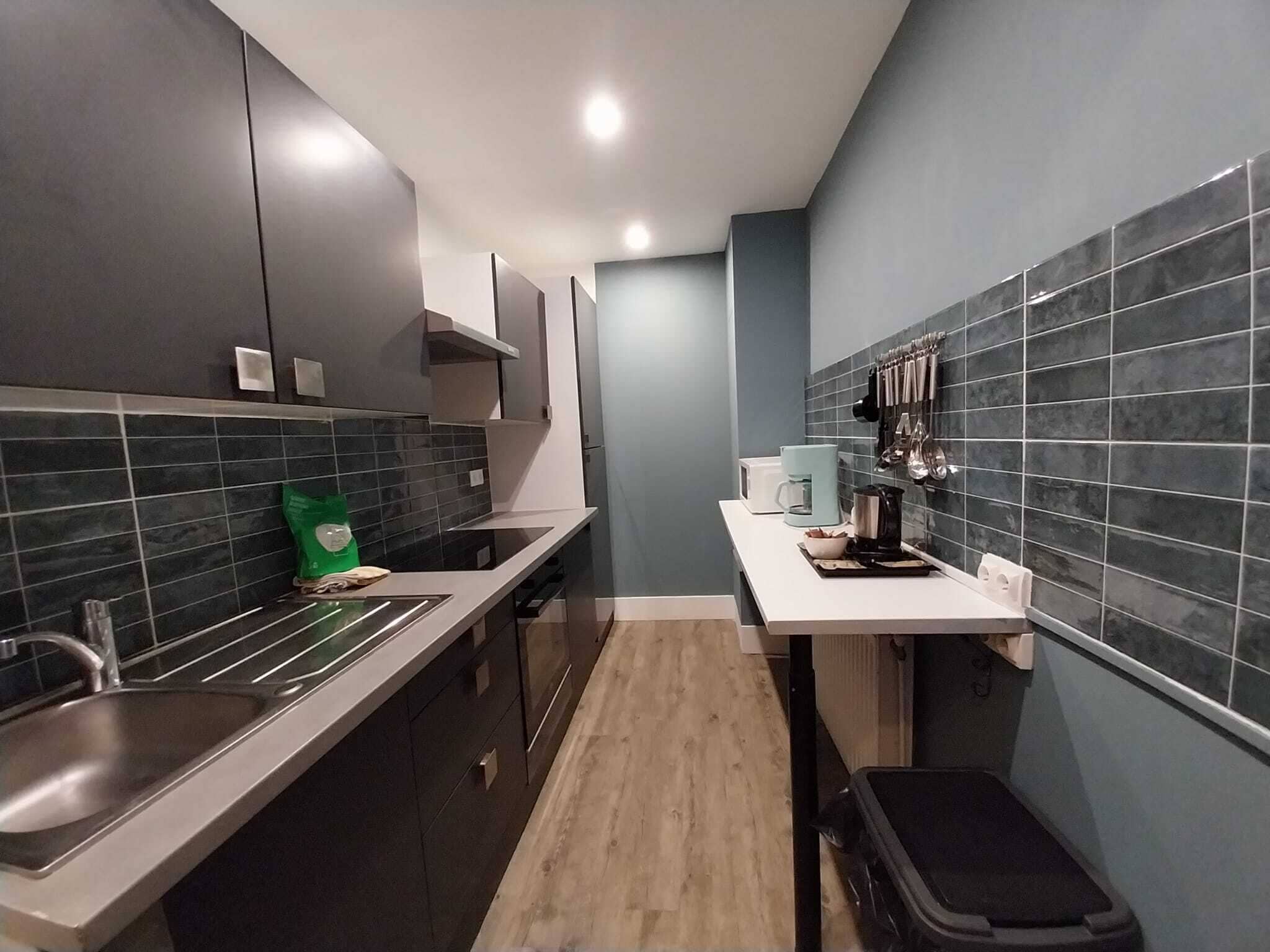 A modern kitchen with dark cabinets, a white countertop, and a tiled backsplash.